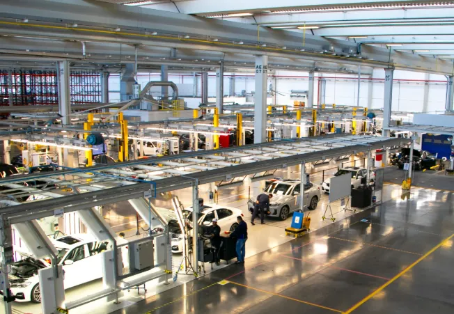 Linha de produção da BMW Group Brasil com carros sendo montados e funcionários trabalhando.