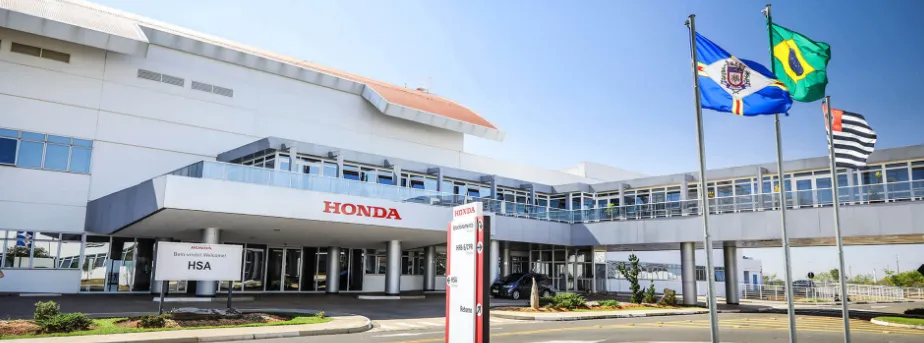 Fachada da unidade Honda com bandeiras do Brasil e do estado ao lado, simbolizando expansão da empresa.