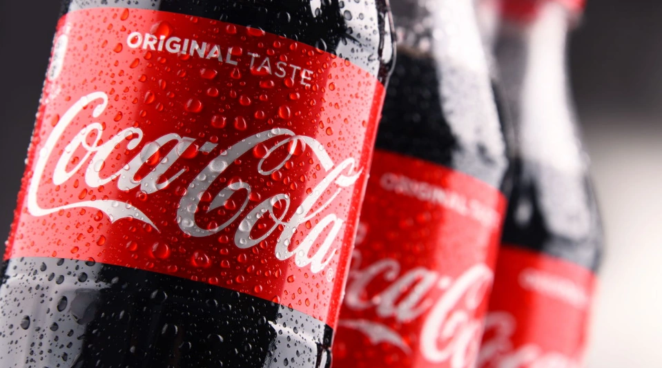 Coca-Cola abre novas vagas de emprego em diversas áreas. Garrafa de Coca-Cola com gotas de água, simbolizando frescor e novas oportunidades de trabalho.